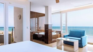 A modern hotel room with a large bed, a sofa, a bathroom with a large mirror, and a view of the sea. - Playasol Aquapark & Spa Hotel (Roquetas de Mar)