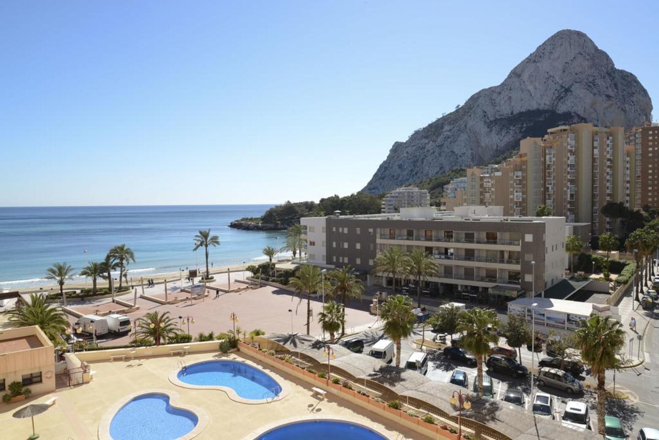 Ein Resort mit Poolbereich, Strand und einem Bergpanorama.
