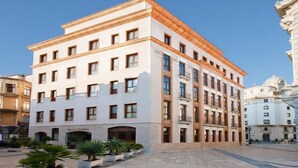 Un hotel de varios pisos con fachada blanca y tejado rojo.