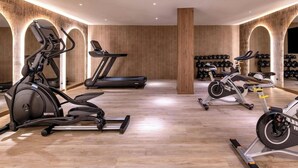 Un gimnasio con equipos de ejercicio variados, incluyendo cintas de correr, bicicletas estáticas y elípticas.