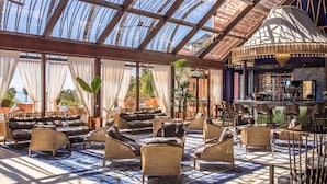 A spacious indoor area with a glass ceiling, wicker furniture, and a bar area. - Hacienda Del Mar Melia Collection (Estepona)