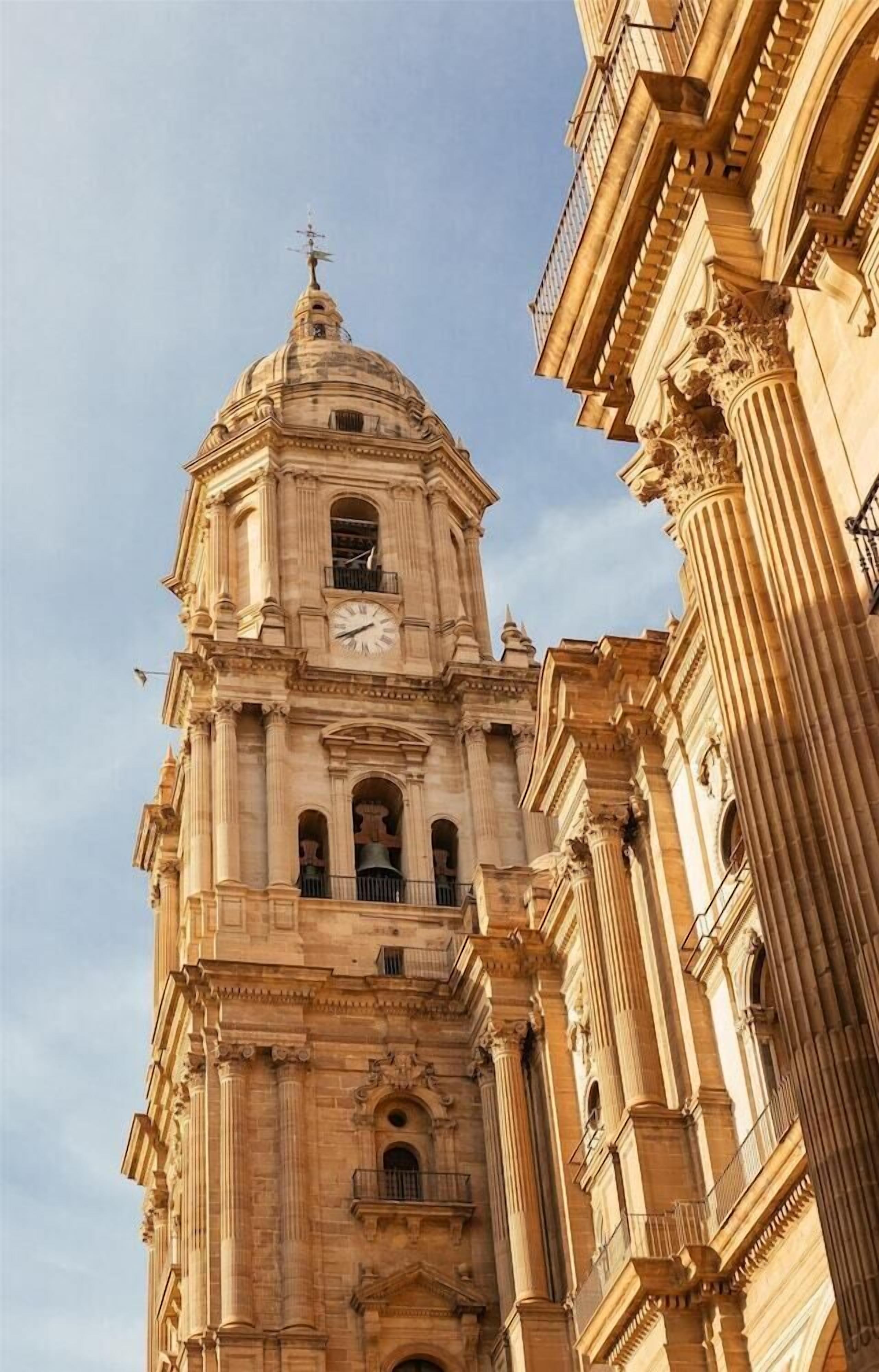 Un edificio alto y ornamentado con una torre de reloj, que presenta elementos arquitectónicos clásicos como columnas y arcos.