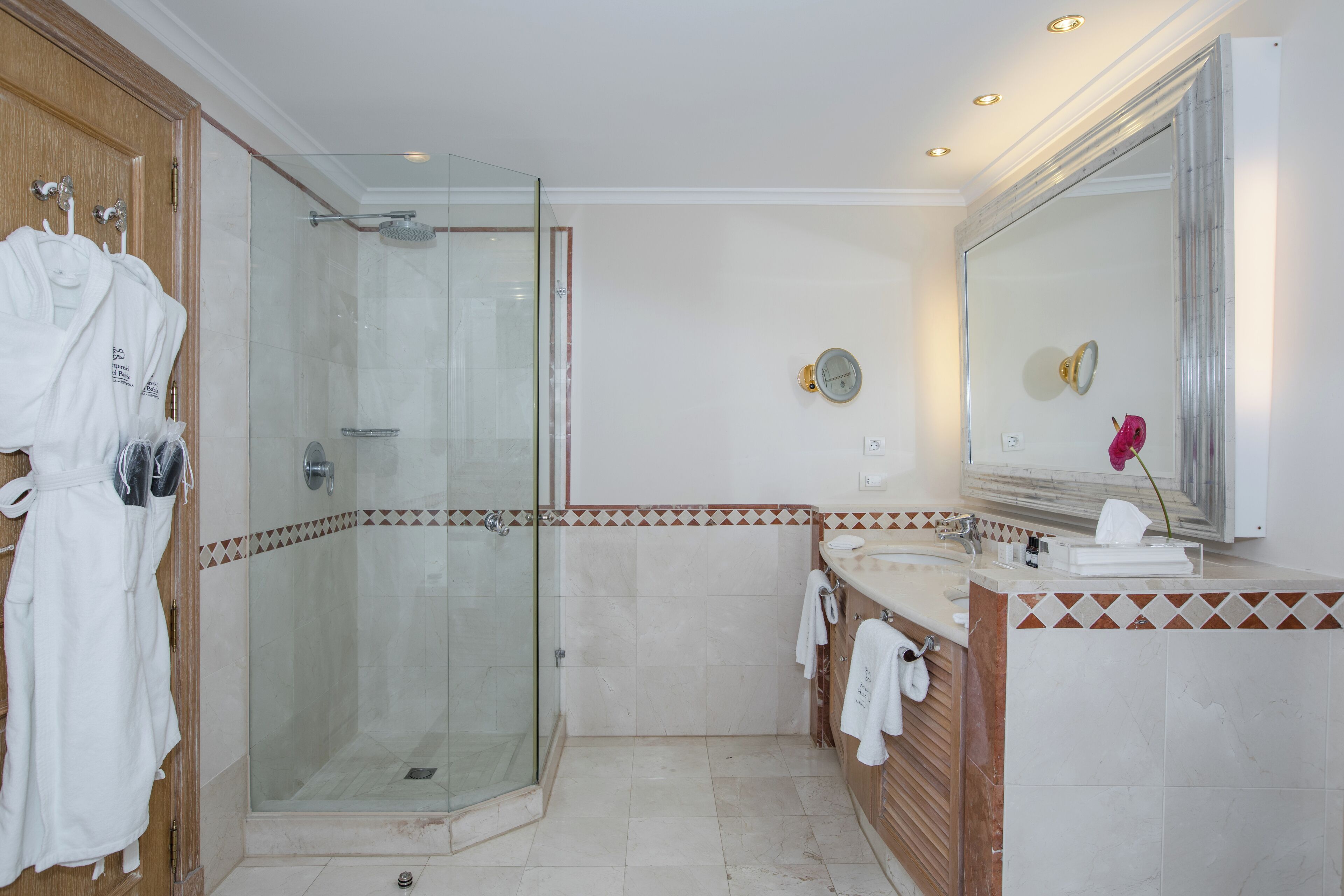 Une salle de bain moderne avec une douche à parois de verre, un meuble-lavabo avec un miroir et un porte-peignoir.