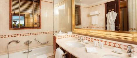 Un baño con bañera, dos lavamanos, un espejo grande y una ventana con persianas.