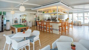 A spacious indoor area with a pool table, bar area with stools, and seating arrangements. - Club Sa Coma (Sant Llorenc des Cardassar)