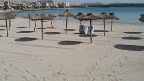 A beach with thatched umbrellas and a row of white lounge chairs. - Club Sa Coma (Sant Llorenc des Cardassar)
