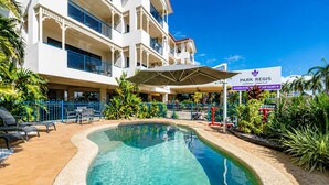 Een hotel met een zwembad, buitenzitplaatsen en een bord waarop 'Park Regis Anchorage - Townsville' staat.