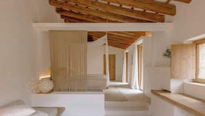 A modern interior with a wooden ceiling, a sofa with cushions, a small table with a book, and a mirror. - Es Raco D Arta, a Member of Design Hotels (Arta)