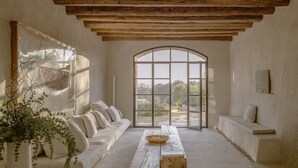 A spacious room with a large arched window, a white sofa, a wooden table, and a potted plant. - Es Raco D Arta, a Member of Design Hotels (Arta)