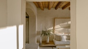 A room with a wooden ceiling, a white sofa, a white bed, and a vase with branches. - Es Raco D Arta, a Member of Design Hotels (Arta)
