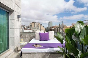 A bed with a white and purple bedding set, a magazine, and sunglasses on the side. - Allegro Barcelona (Barcelona)