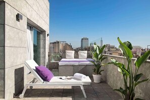 A rooftop terrace with a lounge chair, a small bed, and potted plants. - Allegro Barcelona (Barcelona)