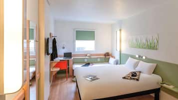 Une chambre d’hôtel avec un lit, un bureau avec un ordinateur portable, une chaise, une télévision et une fenêtre.