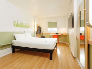 Una habitación de hotel con una cama, un escritorio, una silla, un televisor y una ventana.