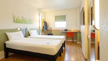 Habitación de hotel con dos camas, un escritorio, una silla, una ventana y un cuadro en la pared.