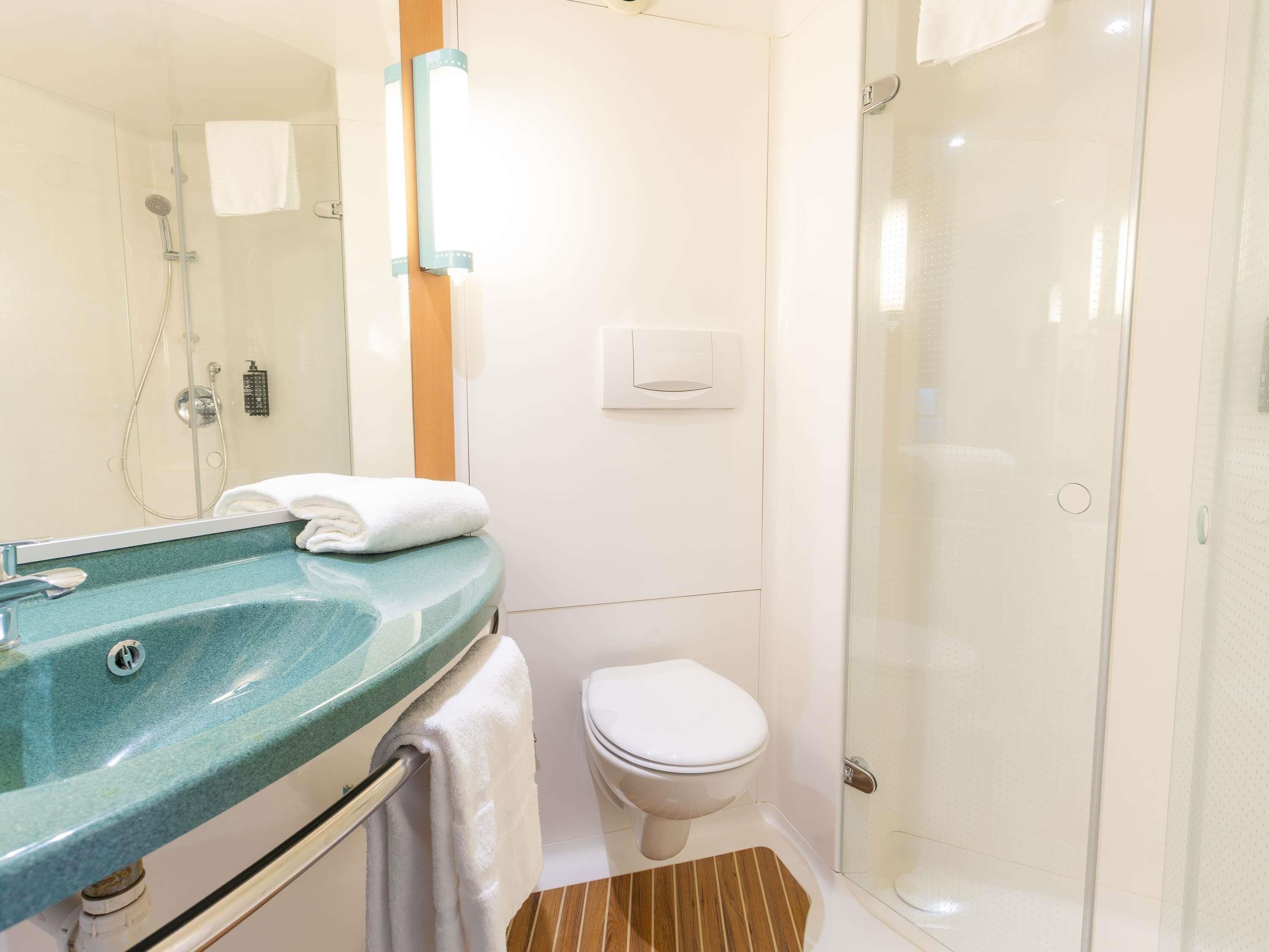 Une salle de bain avec une douche à parois de verre, des toilettes blanches et un lavabo avec une serviette.