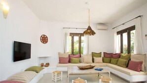 Una sala de estar moderna con un sofá blanco, una mesa de centro y un televisor montado en la pared.