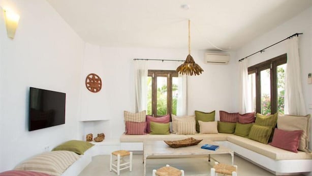 Una sala de estar moderna con un sofá blanco, una mesa de centro y un televisor montado en la pared.