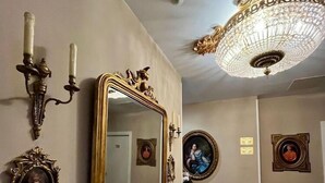 A hallway with a large ornate mirror, wall sconces, and a chandelier. - El Palacete de Almudayna (Madrid)