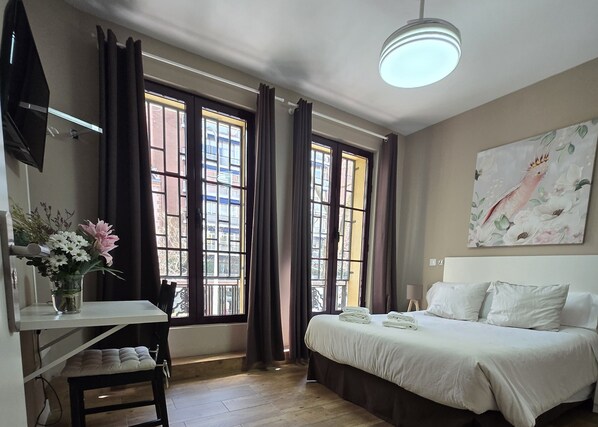 Une chambre à coucher avec un lit, un bureau et une fenêtre avec des rideaux.