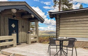 Eine Holzhütte mit Veranda, zwei Korbsesseln und einem Tisch.