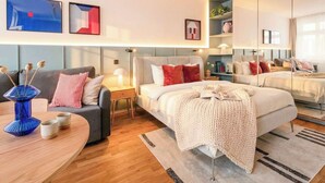 Ein modernes Hotelzimmer mit einem großen Bett, einer Couch, einem Beistelltisch und einem Spiegel.