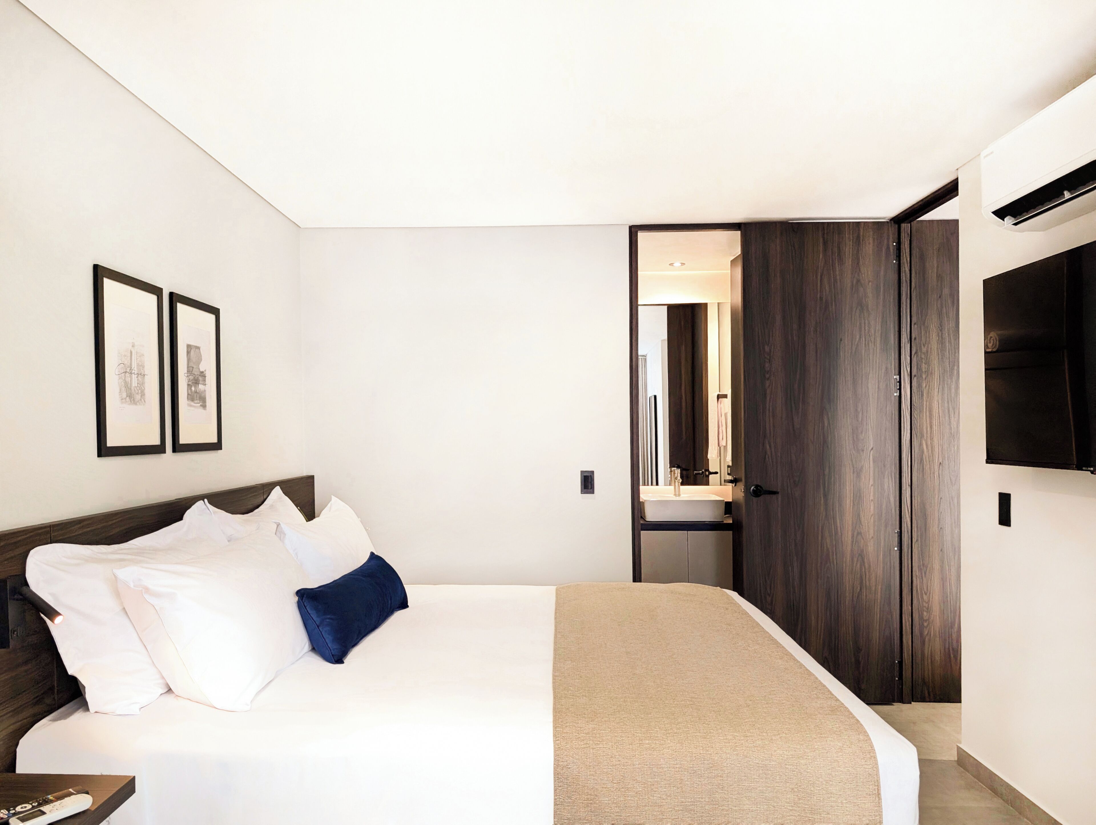A bedroom with a bed, a bedside table, a TV, and a wardrobe.