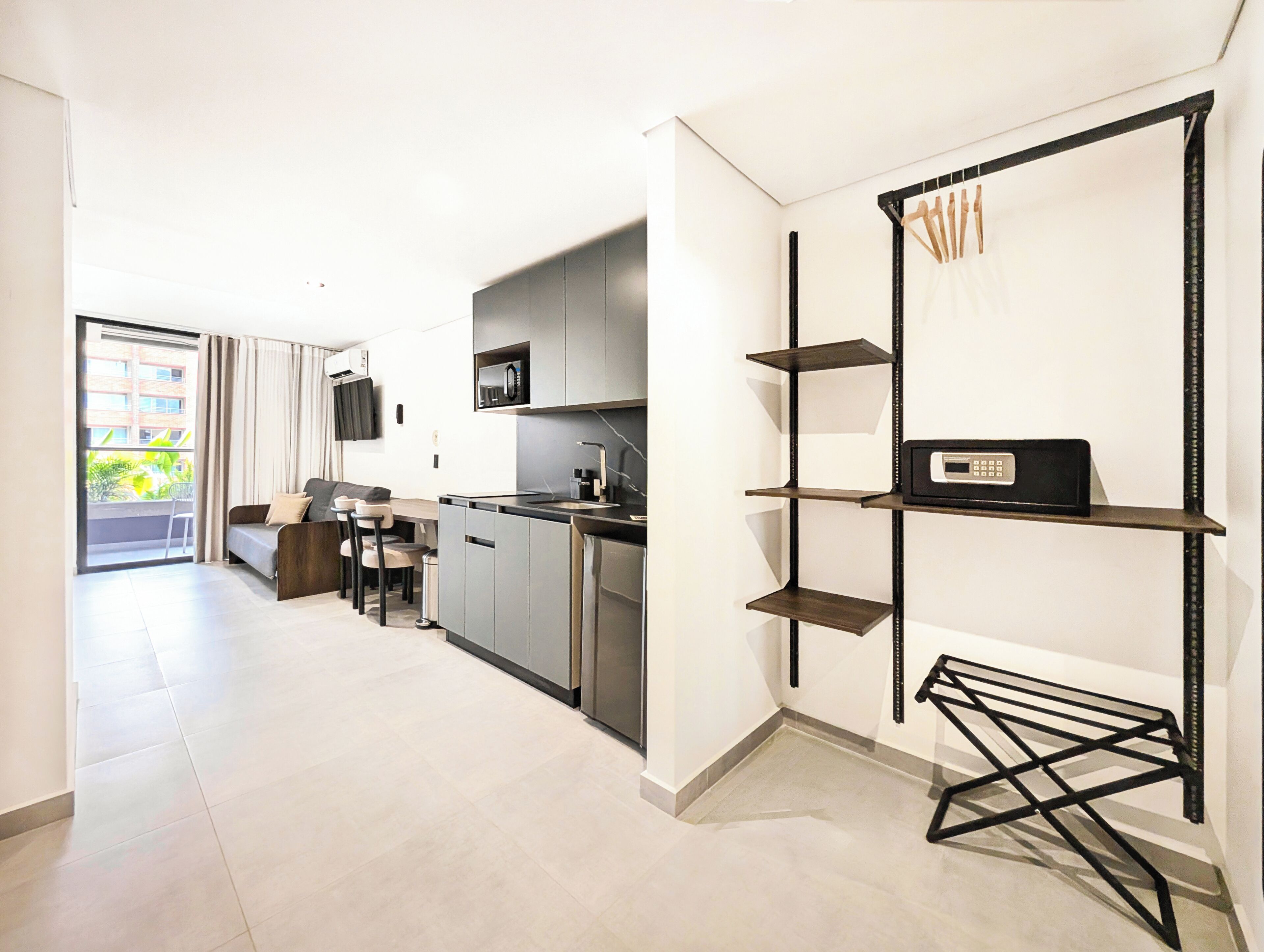 Una cocina moderna con microondas integrado, un comedor con sofá y sillas, y un balcón con cortinas.