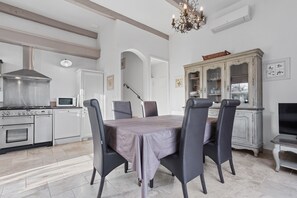 A dining area with a table set for four, a kitchen with modern appliances, and a vintage cabinet. - Le Mas des Bouteillans “Les Myrtes” with Wi-Fi and Air Conditioning (La Cadière-d'Azur)