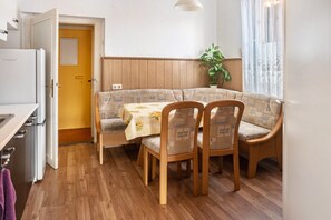 Une cuisine compacte comprenant un réfrigérateur, un coin repas avec une table et des chaises, un meuble en bois et une porte donnant sur une autre pièce.