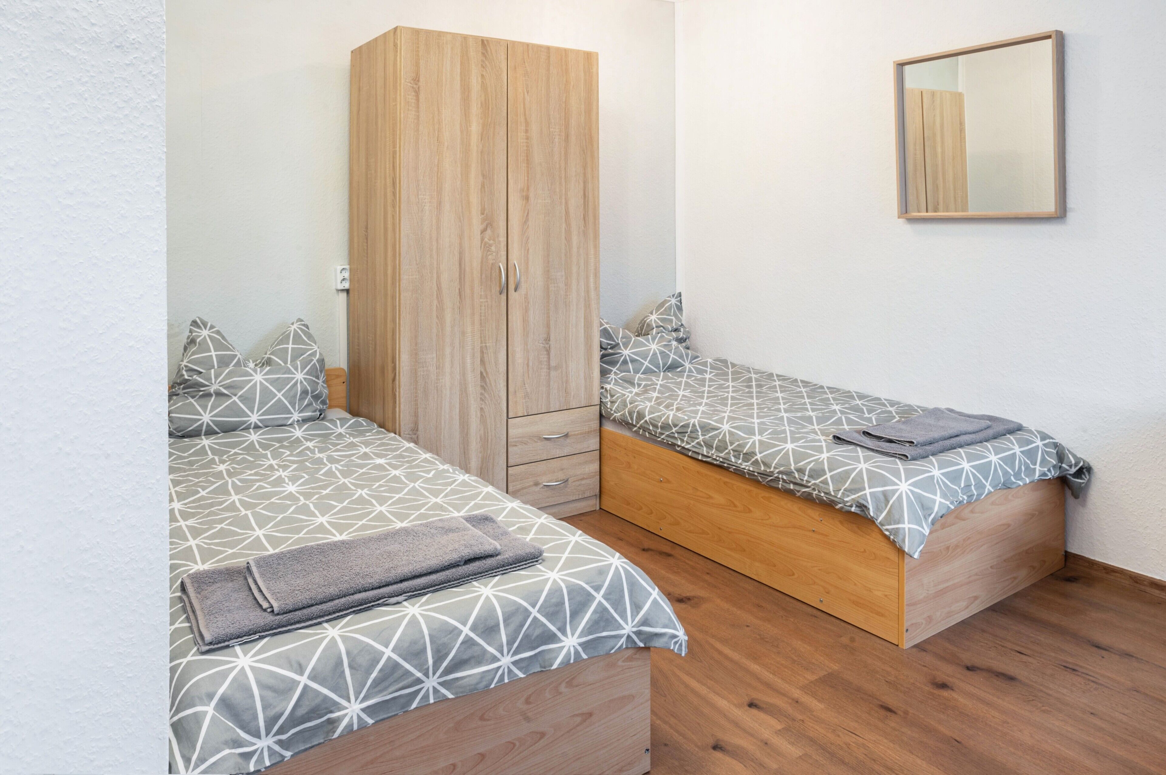 Une chambre avec deux lits, une armoire et un miroir.