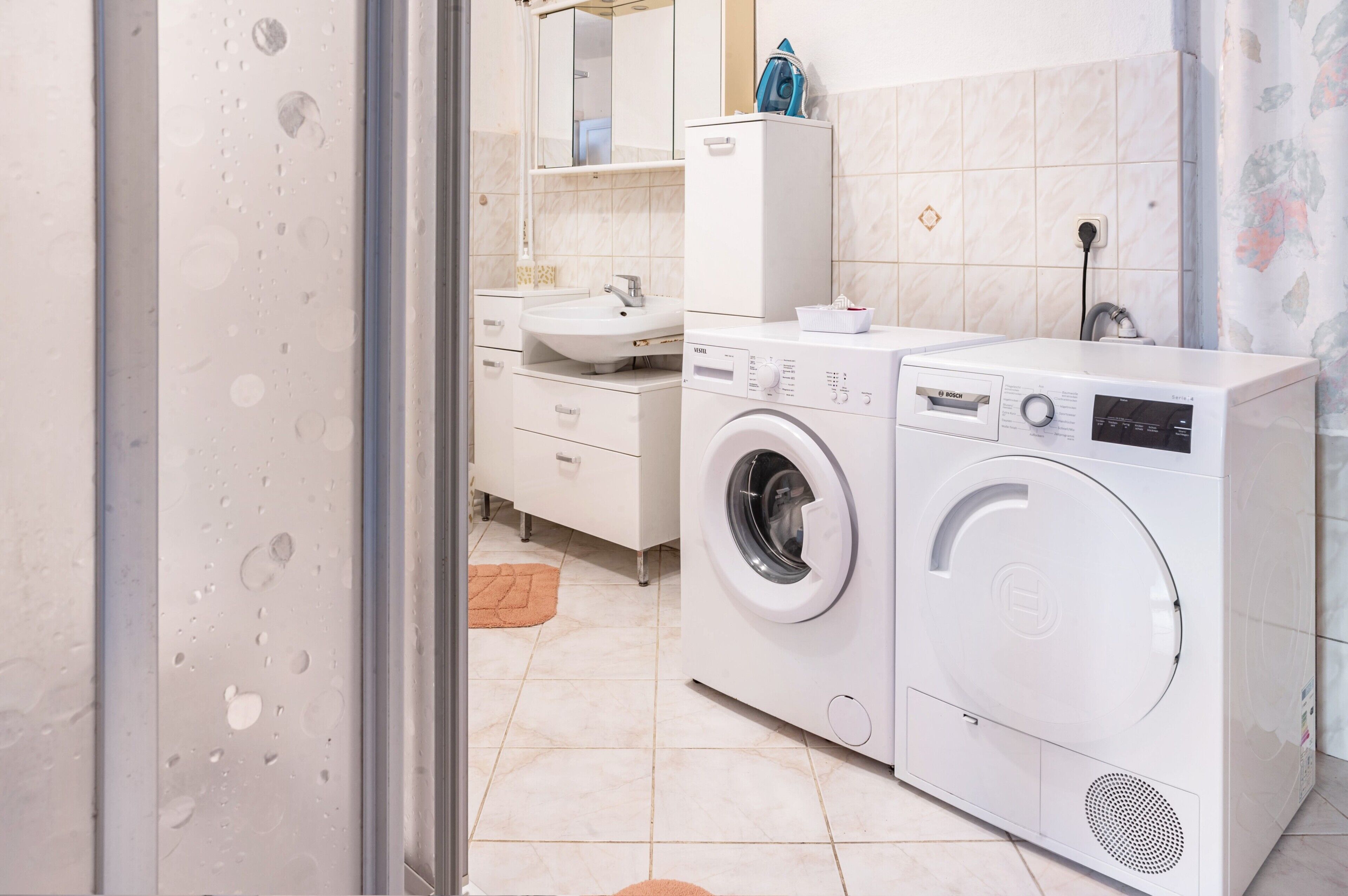 Un bagno moderno con lavatrice, lavandino e specchio.