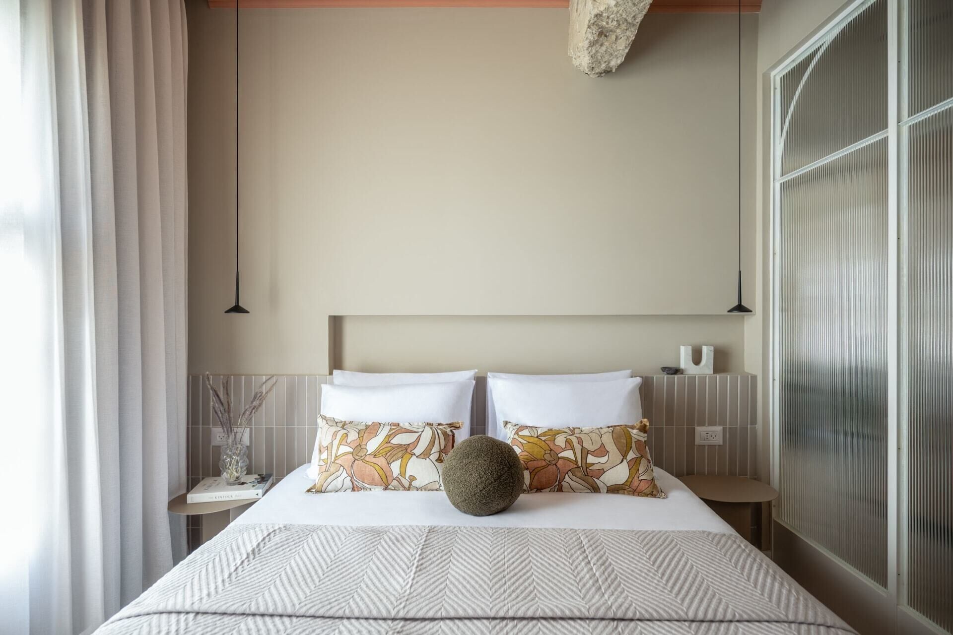 Un letto rifatto con cura, lenzuola decorate, un cuscino ornamentale e un oggetto rotondo sopra il letto.
