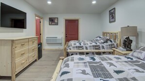 A bedroom with two beds, a wooden dresser, a TV, and a red door. - Lundy's Black Bear - Blair Oaks (Drummond)