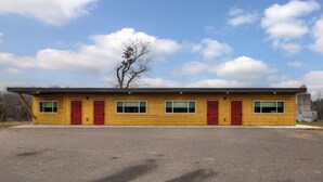 A two-story wooden building with red doors and windows, a flat roof, and a parking lot in front. - Lundy's Black Bear - Blair Oaks (Drummond)