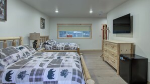 A bedroom with two beds, a dresser, a TV, and a window with a view of trees. - Lundy's Black Bear - Blair Oaks (Drummond)