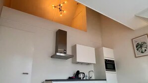 A modern kitchen with white cabinets, a built-in oven, and a coffee maker on the counter. - Lodge Located on the Church Square (Zoutelande)