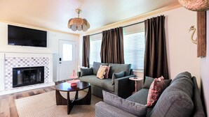 Ein Wohnzimmer mit Kamin, einer Sofagarnitur, einem Fernseher und einem Deckenventilator.