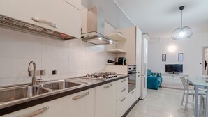 Una cucina moderna con piano cottura a gas, lavello in acciaio inossidabile e mobili bianchi.