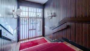 Una scala con un tappeto rosso che porta a una porta con un vetro.