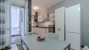 Una cucina moderna con mobili bianchi, un frigorifero bianco e un tavolo da pranzo con sedie.