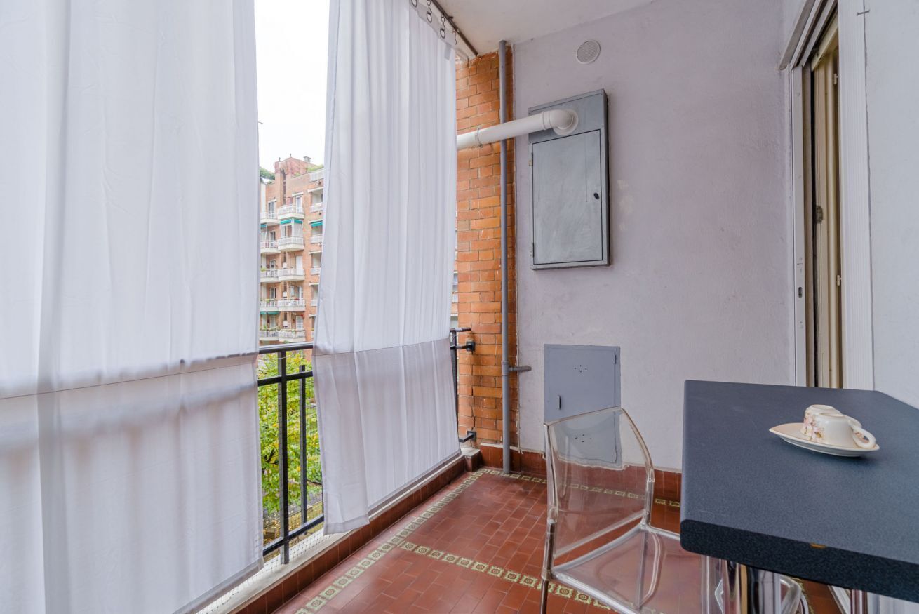 Ein Balkon mit Blick auf Gebäude, ein Tisch mit einer Tasse und ein Stuhl.