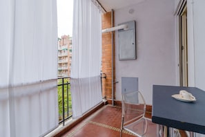 Een balkon met uitzicht op gebouwen, een tafel met een kopje en een stoel.