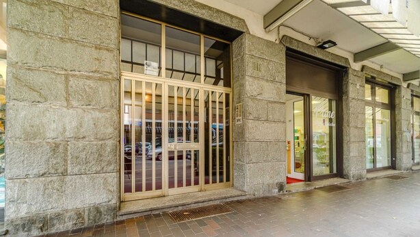 L'ingresso di un edificio con pareti in pietra, un cancello in metallo e una porta in vetro.