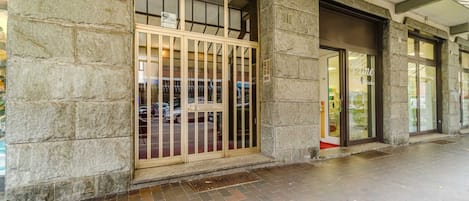 A building entrance with stone walls, a metal gate, and a glass door.