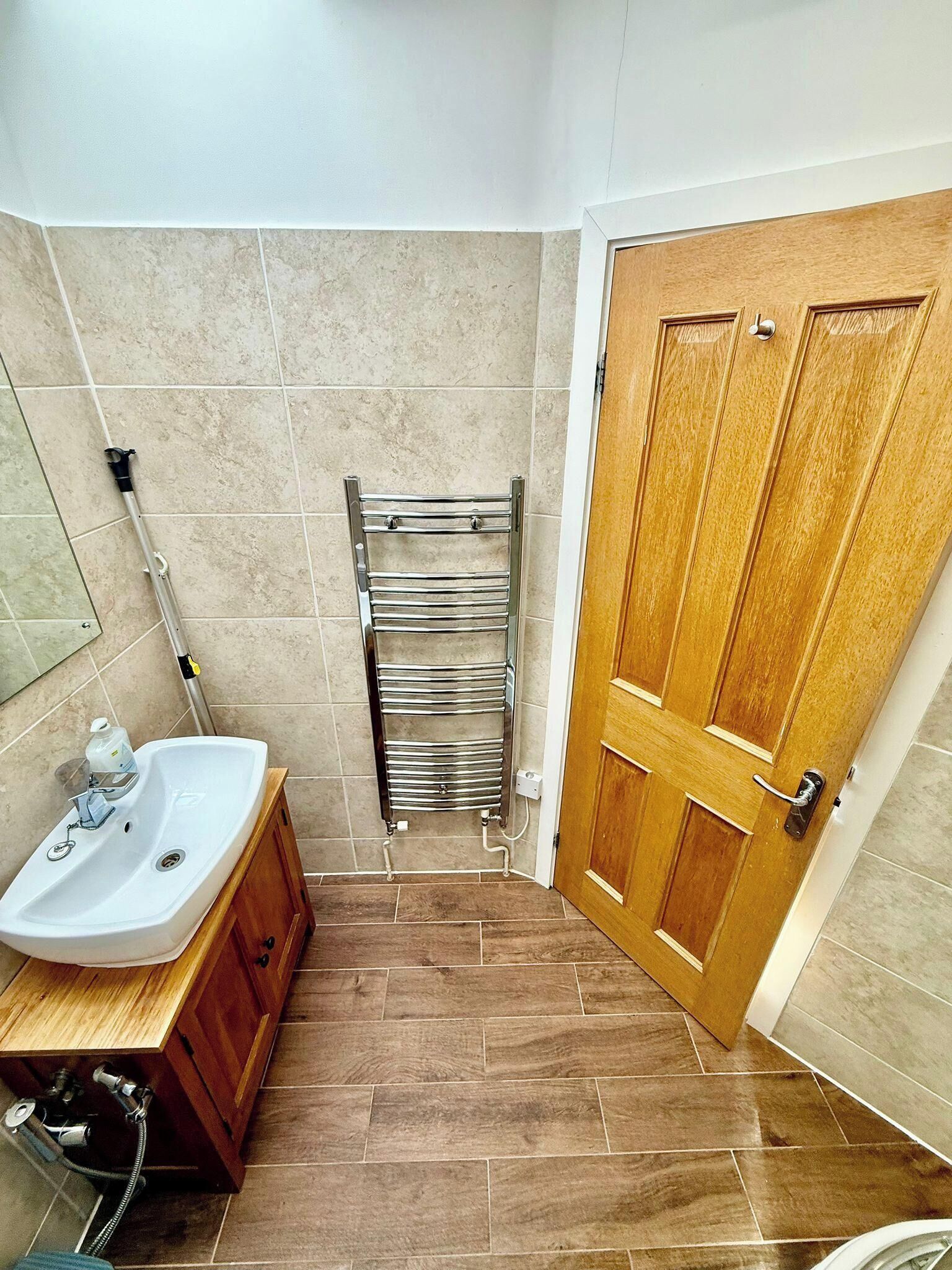 Une salle de bain avec un lavabo, un meuble en bois, un porte-serviettes et une porte en bois.