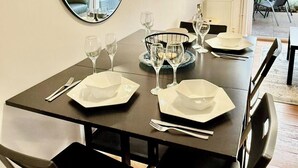 A dining area with a table set for four, a large mirror, a television, and a view of the outdoor patio. - 2 Bed House - Sleeps 4 - Parking - Wifi (Cambridge)
