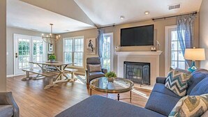 Un salon avec une cheminée, un téléviseur et un coin repas comprenant une table et des chaises.