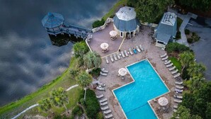 Vue aérienne d’un complexe hôtelier doté d’une piscine, de chaises longues, de parasols et d’un toboggan aquatique.