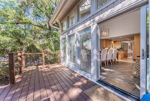 A wooden deck with a glass door leading to a modern kitchen and dining area. - Elegant Sea Pines Getaway Near the Beach! (Hilton Head Island)